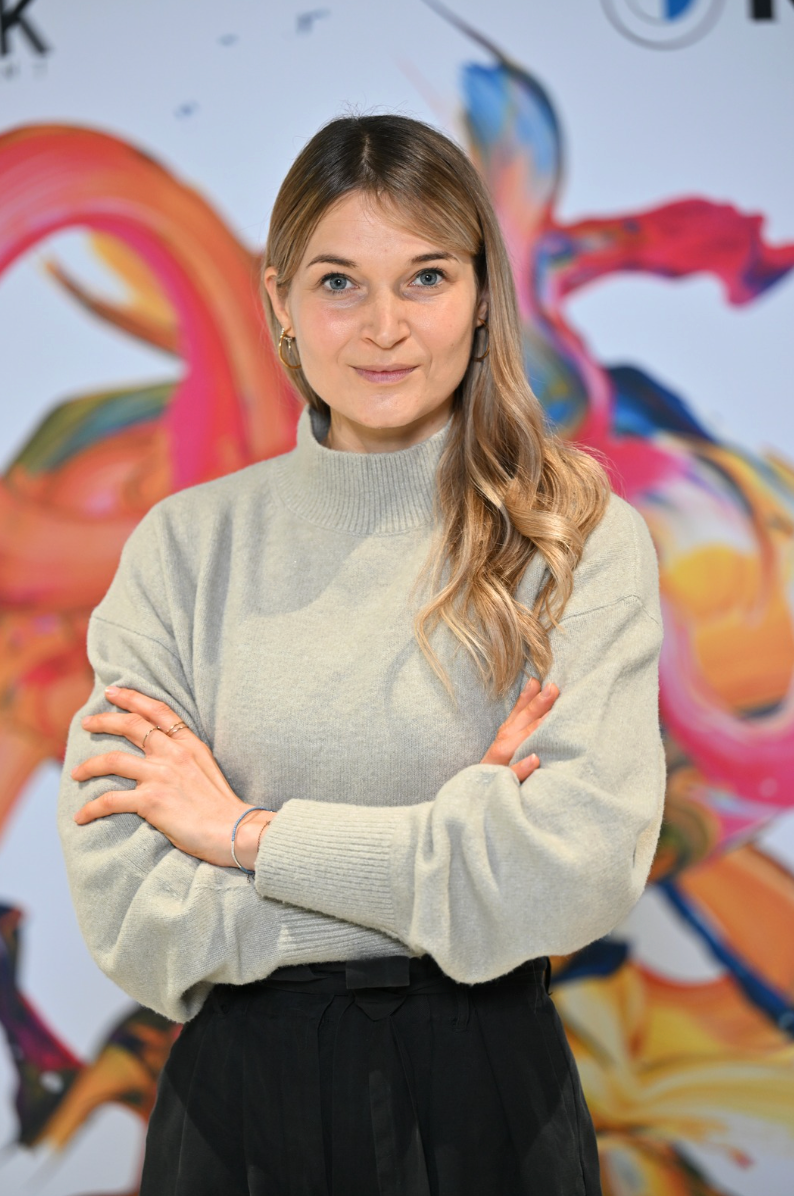 Portrait der Mainzer Künstlerin Isabelle Breitkopf, vor farbintensiver abstrakter Malerei